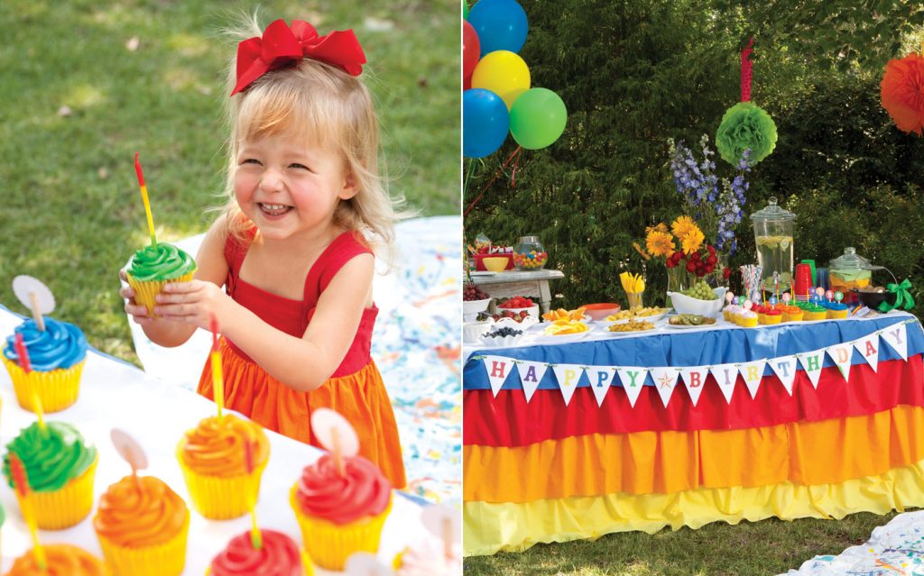 Photo of a child with a cupcake and table at a rainbow birthday party