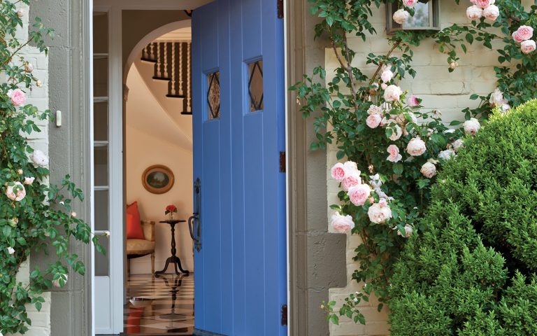 Blue front door framed by crawling roses