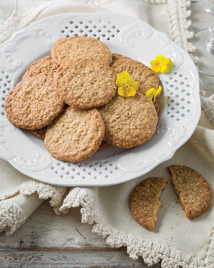 Old-Fashioned Goodies Benne Wafers served in a white perforated dish and topped with small yellow flowers