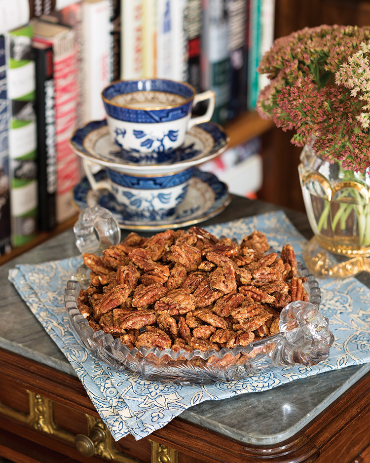 Autumn Spiced Pecans in a glass dish atop a blue-and-cream linen