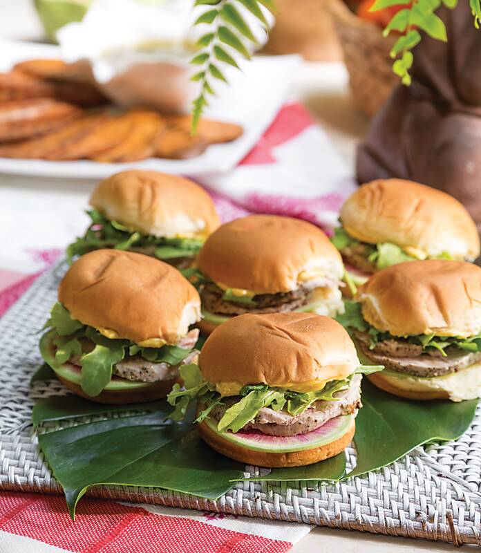 Six pork sliders on a bright green leaf and wicker tray