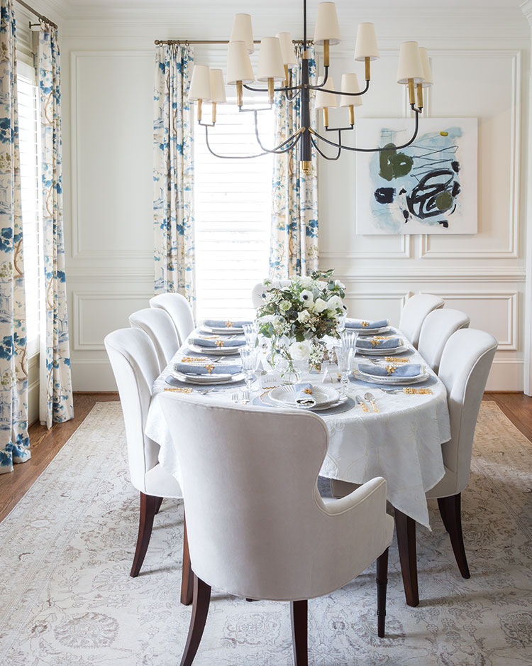 An all-white dining room with blue floral draperies