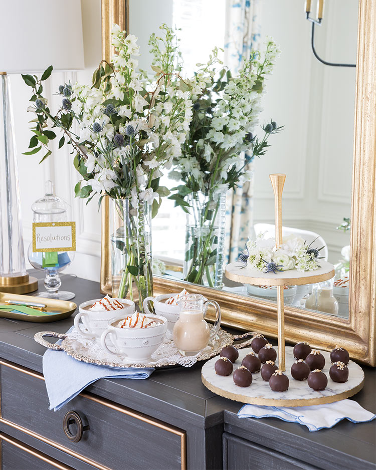 Deserts and coffee drinks on a sideboard with a tall floral arrangement