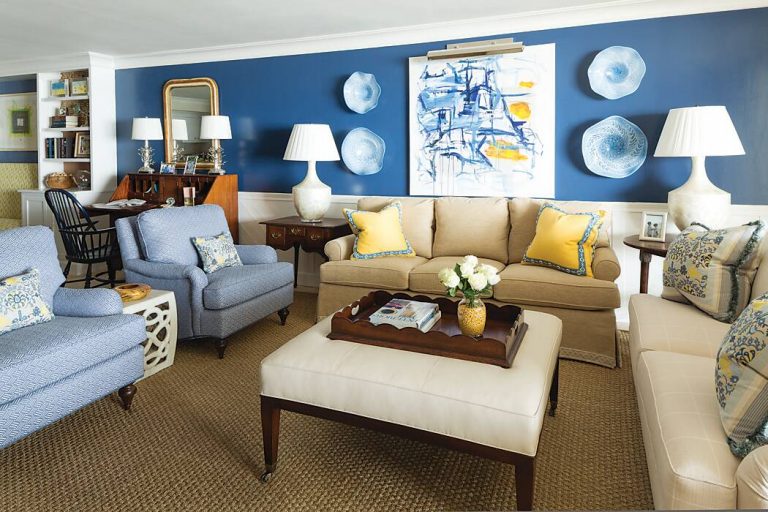 Living room with blue walls, cream sofas, pale blue armchairs, and yellow accents