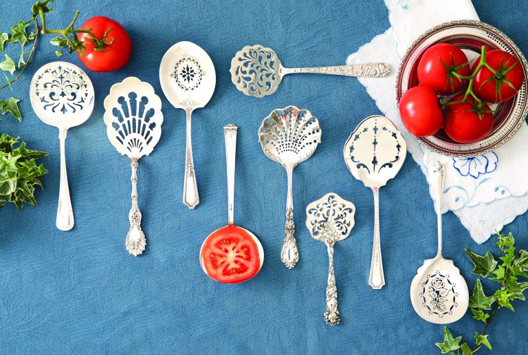 A lineup of various silver tomato servers on blue backdrop