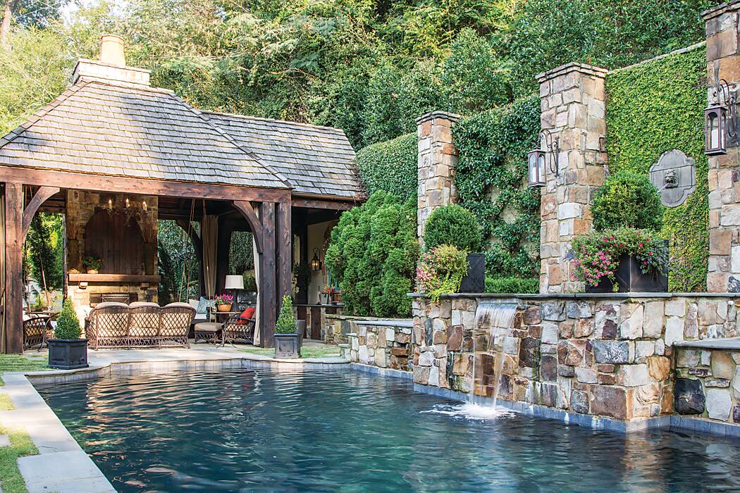 A pool surrounded by a grotto fountain, stonework, and vine-covered walls