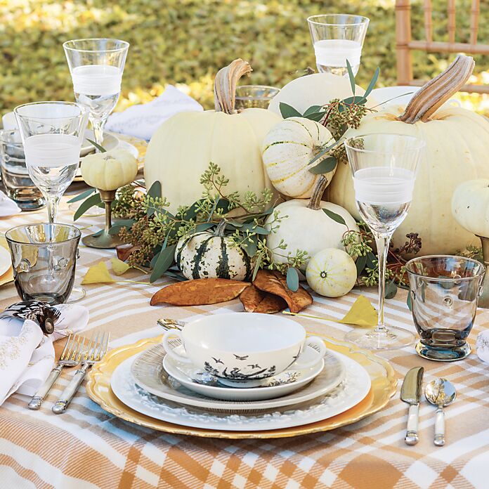 Cream pumpkins at the center of a table set with black-and-white china