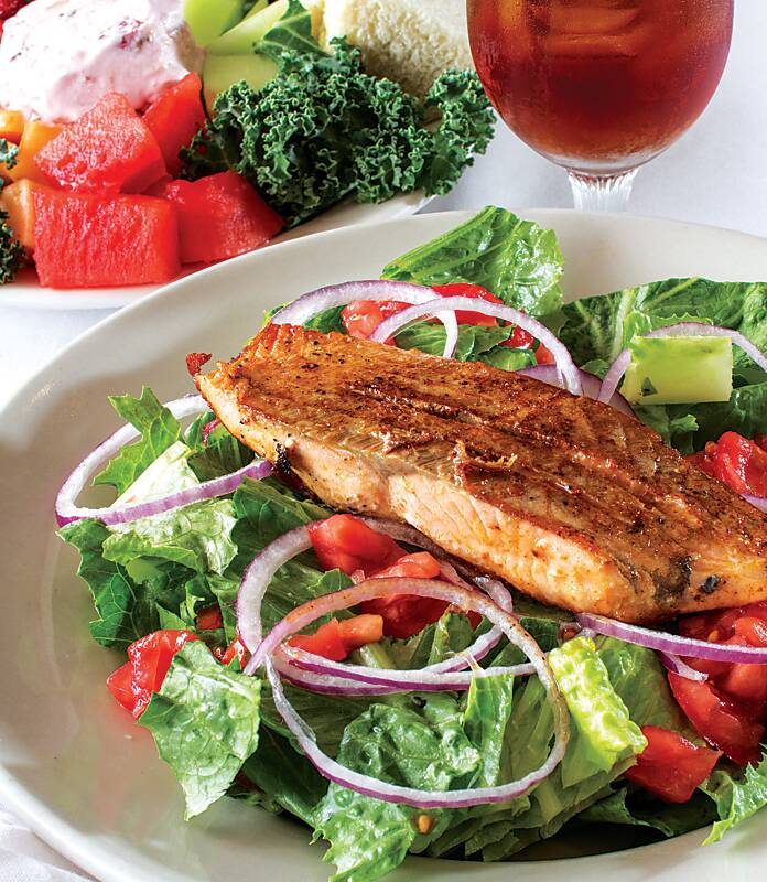 Plated salad topped with cooked fish fillet at The Crystal Grill