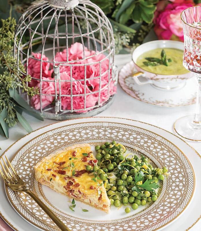 A slice of bacon-onion tart and smashed green peas on a gold-and-white plate 