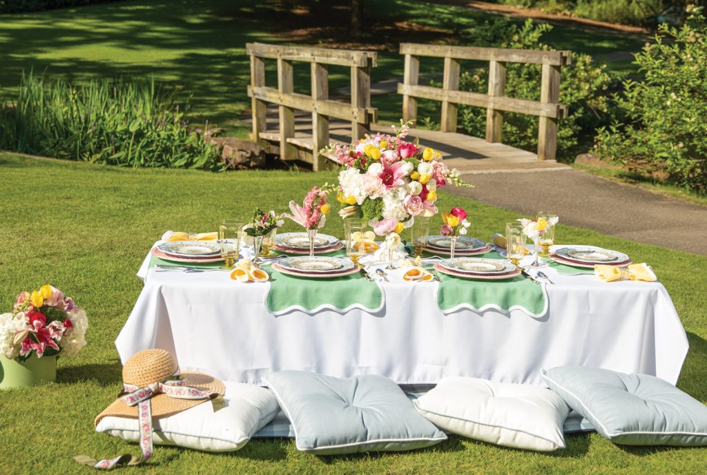Table set with linens and cushions for a picnic by a bridge