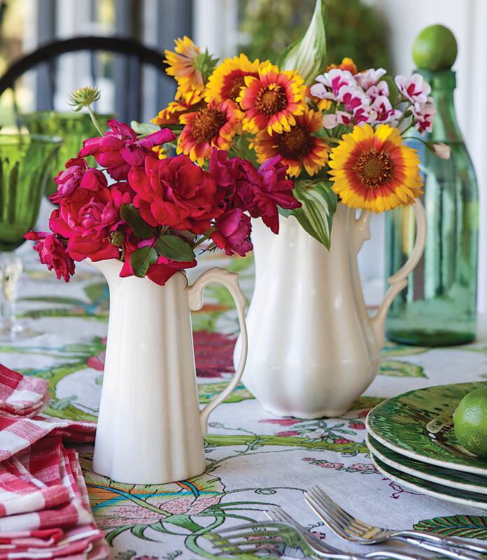 Two white pitchers filled with red and yellow flowers