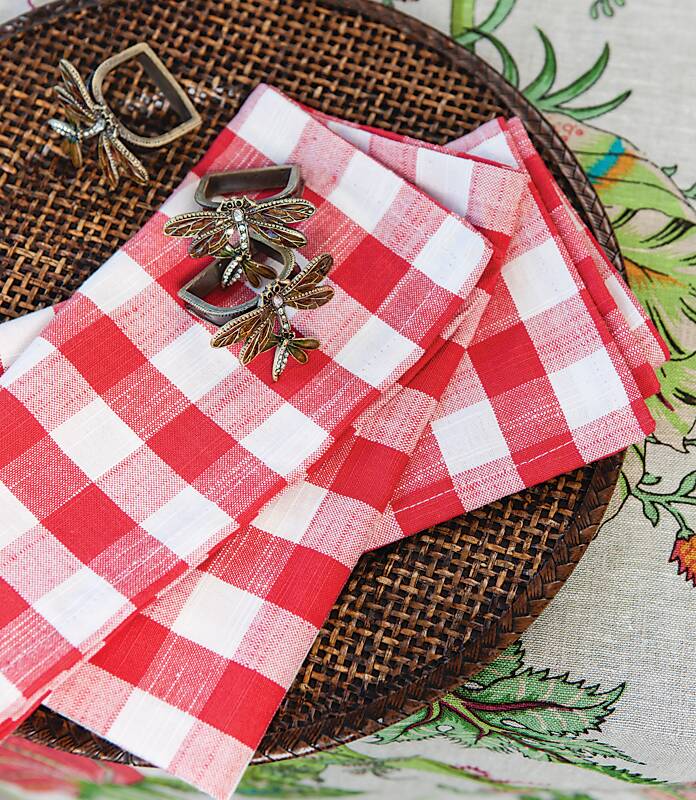 Red-and-white gingham napkins topped with brass dragonfly napkin rings