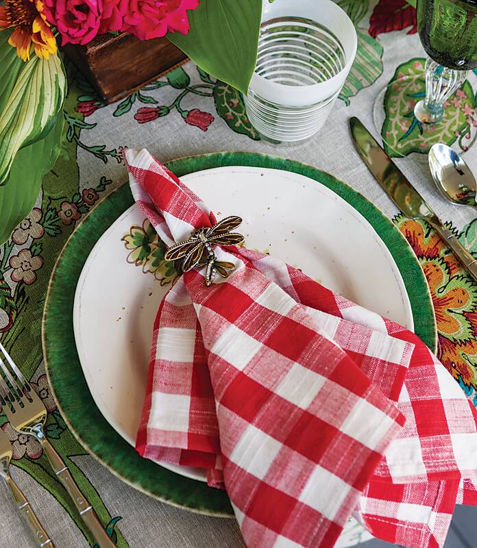 A green and white place setting topped with a red-and-white gingham napkin