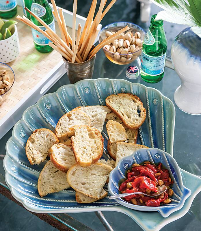 A blue scallop-shaped serving dish with sliced bread and a red pepper dip