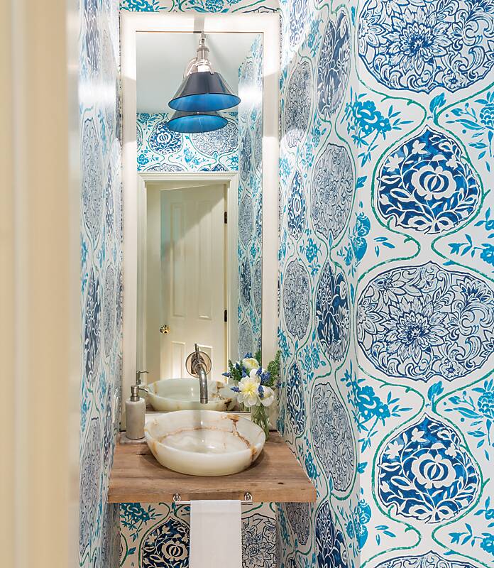 A powder bath cloaked in blue, green, and white block print wallpaper