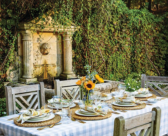 Blue, white, and yellow table setting in front of a garden fountain