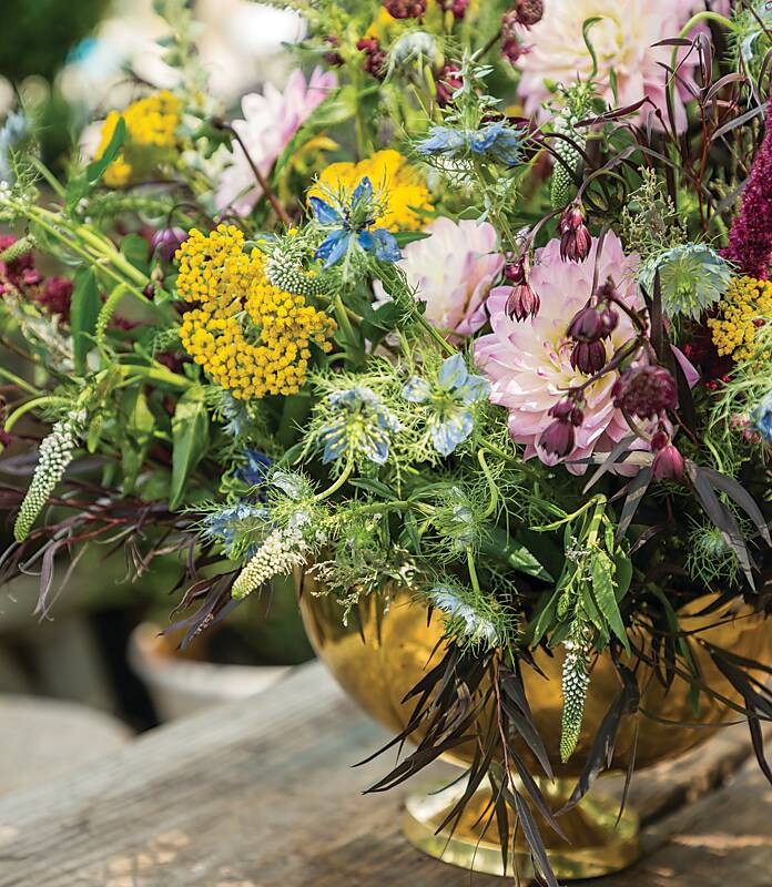 A floral arrangement in a gold footed vessel for a greenhouse gathering