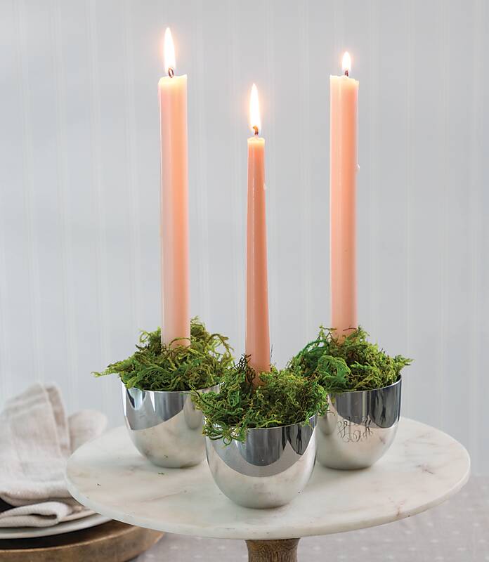 Jefferson cups filled with floral moss hold peach-colored taper candles