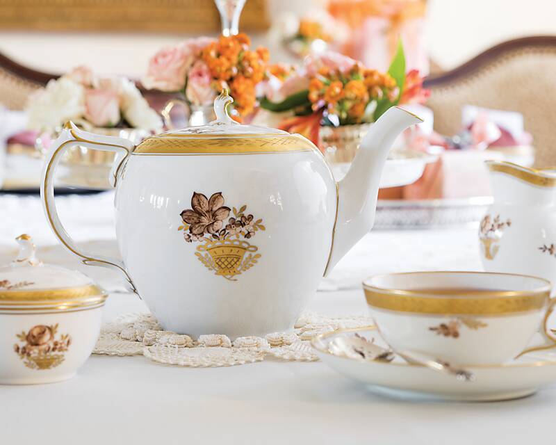 A gold-and-white teapot, cup, and saucer for tea with grandmothers and granddaughters