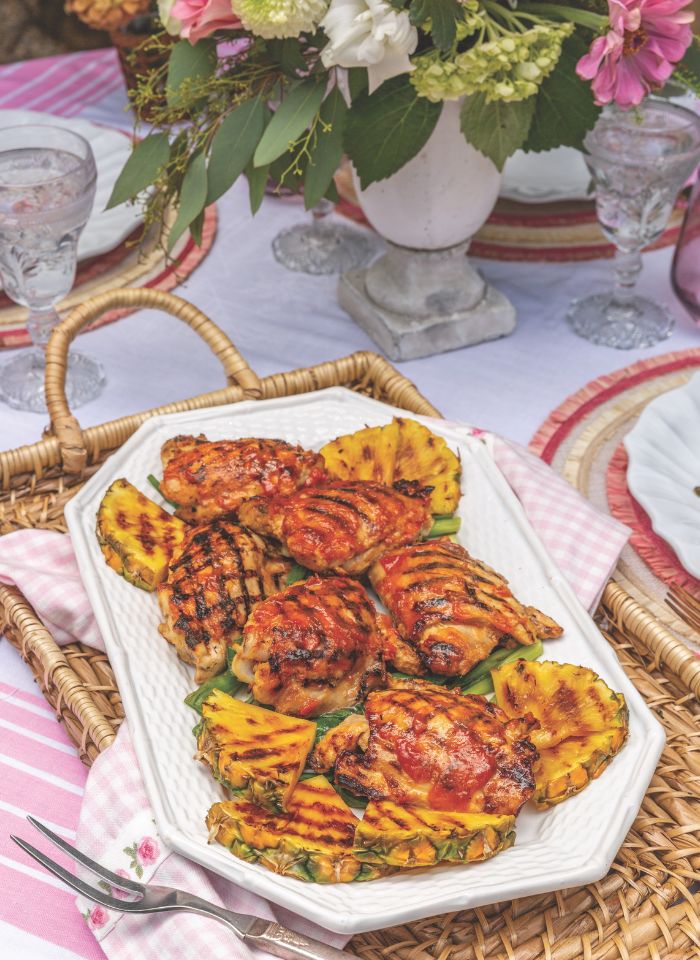 Pineapple Chicken Thighs on a white platter and wicker tray