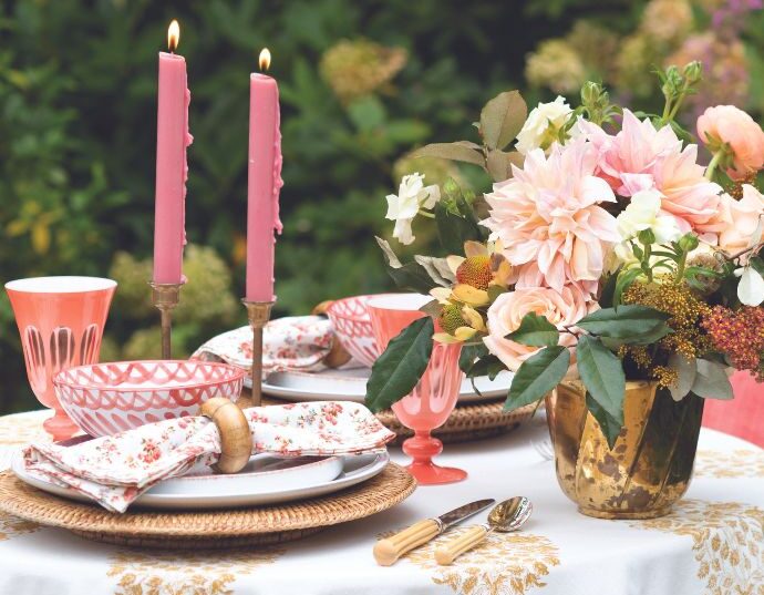 Gold, coral, and white outdoor table setting for charcuterie in the garden