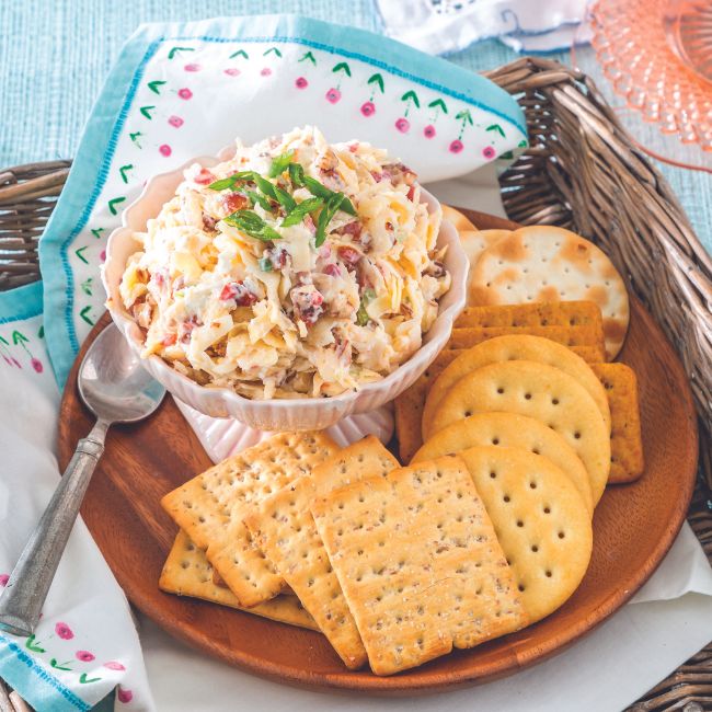 Goat Cheese and Smoked Gouda Pimiento Cheese Spread in a bowl surrounded by assorted crackers