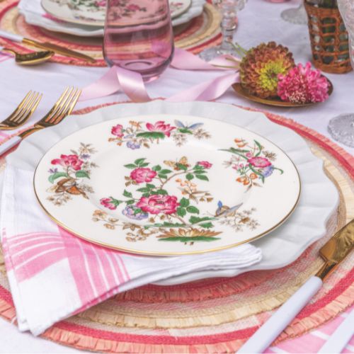 Floral china on a pink-trimmed raffia place mat