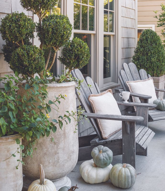 Adirondack chairs on a porch with neutral pumpkins