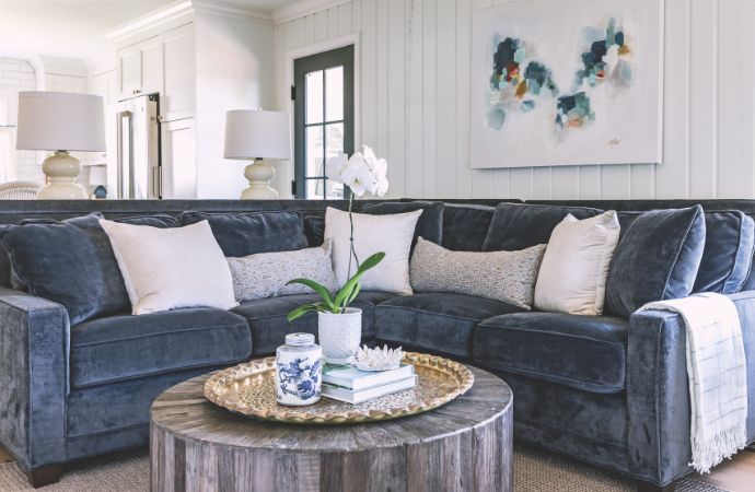 A white wood paneled living room with a blue velvet sofa