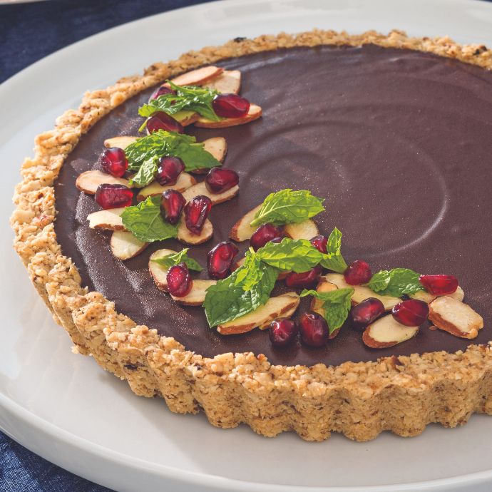 Chocolate tart garnished with pomegranate seeds and mint