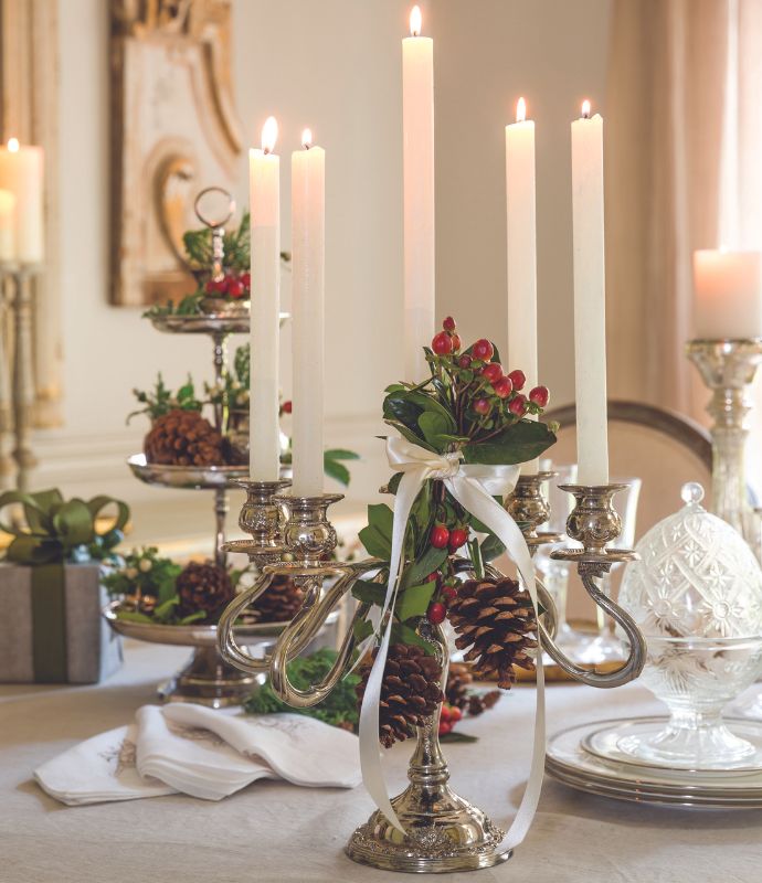 Silver candelabra decorated with pine cones, berries, and ribbon