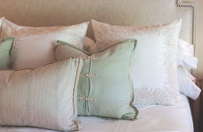 Cream, white, and pale-green throw pillows on a bed