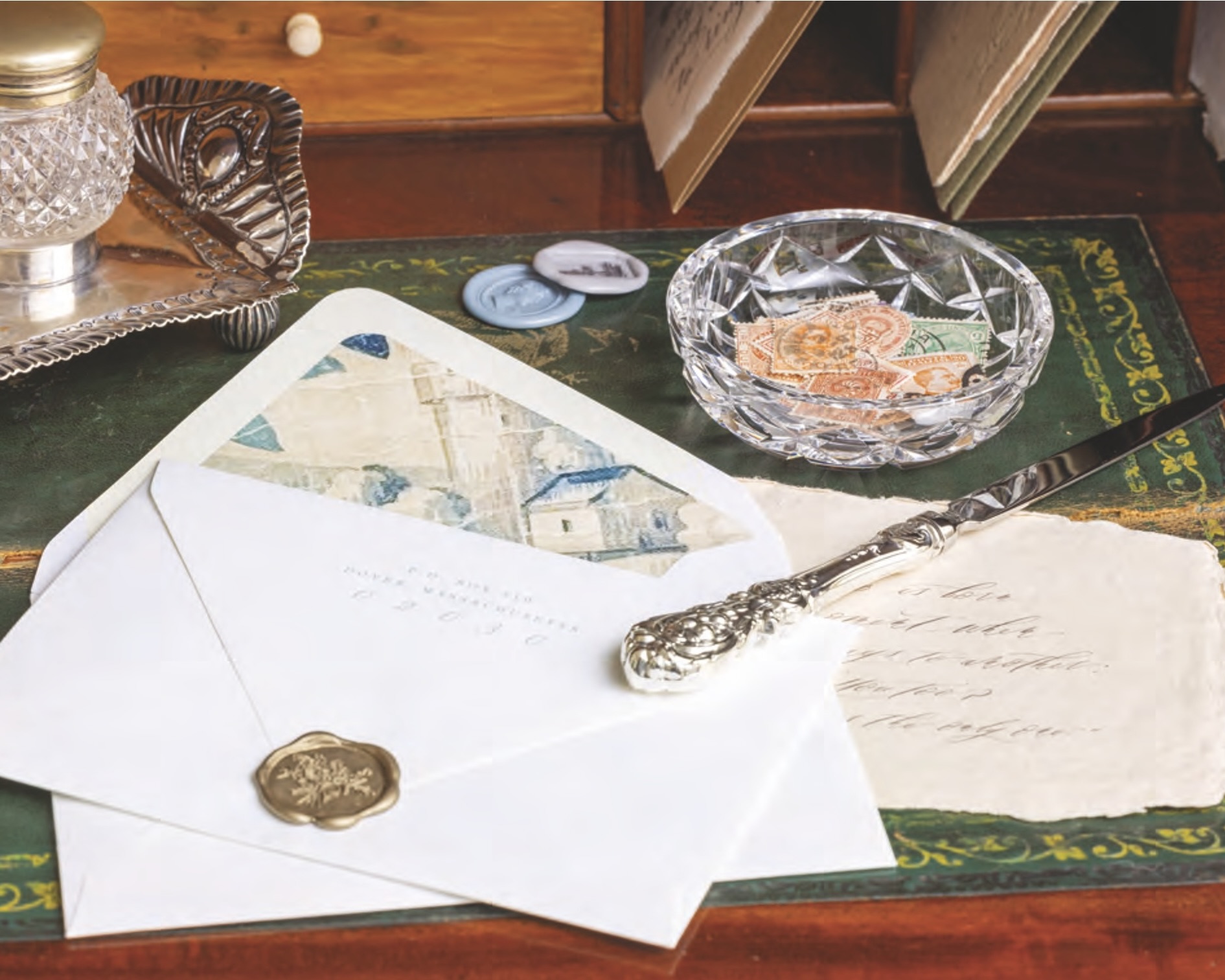 Vintage butter pat styled on a desk as a stamp container