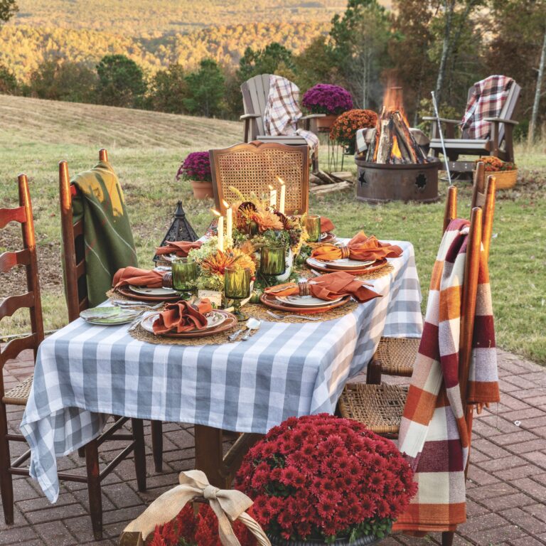 An outdoor table set near a firepit for a fireside supper