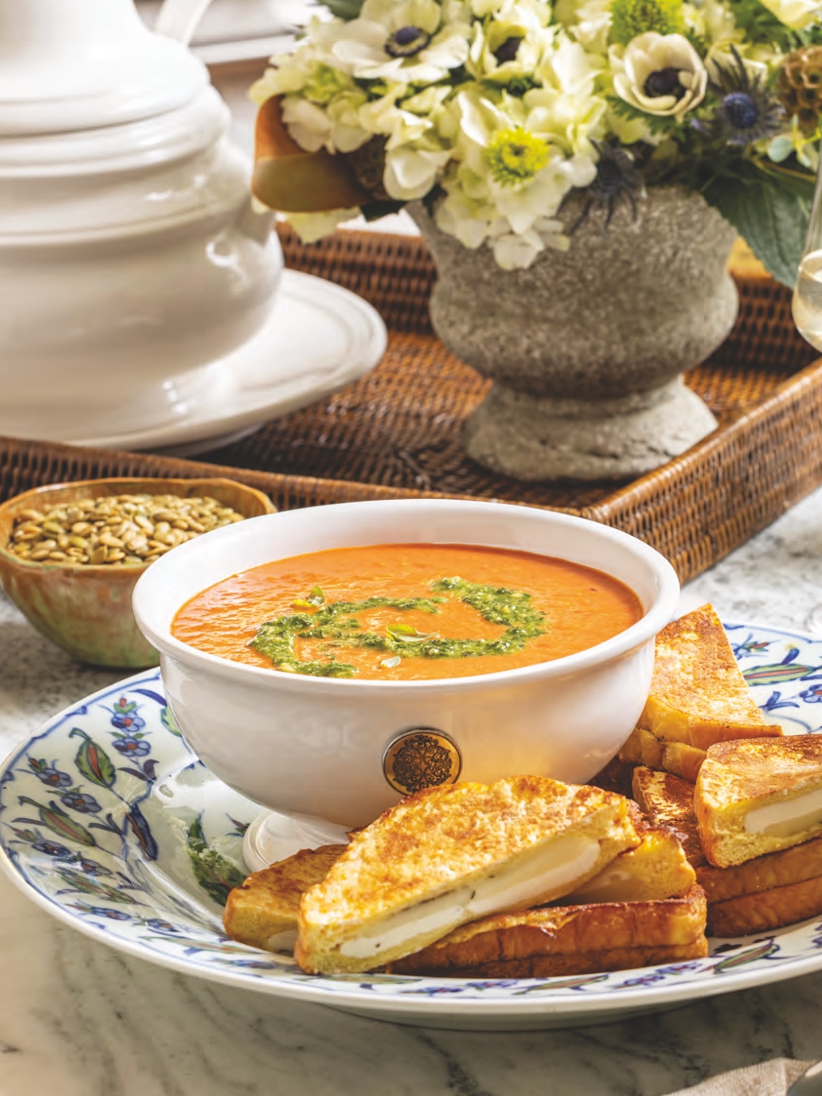 Rosted Tomato Soup with Basil Pesto in a bowl with grilled cheese sandwiches.
