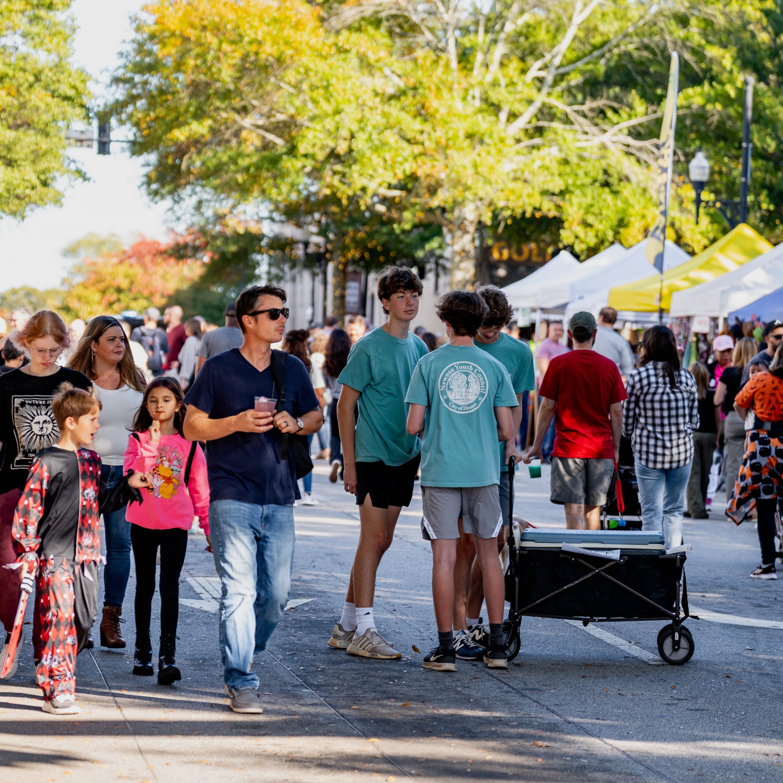 Families including children in Halloween costumes stroll outdoors at Spirit and Spice Festival in Newnan, Georgia.