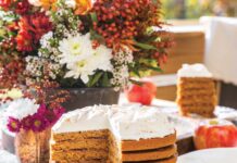 Apple Stack Cake Apple Stack Cake topped with whipped cream and filled with apple butter, on an alfresco table with a fall flower arrangement.