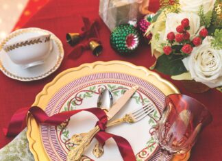 New Looks for Festive China A Christmas place setting consisting of Pickard's Winter Festival salad plate, Wedgwood's Anthemion Ruby dinner plate, a gold charger, and an embroidered napkin with a red tinted goblet.