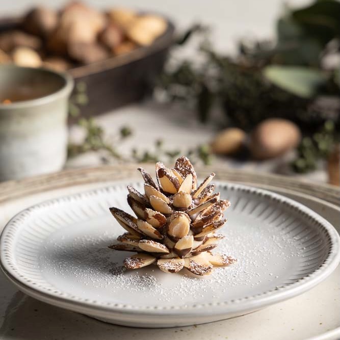 A pine cone made from marzipan and almonds, dusted with powdered sugar.