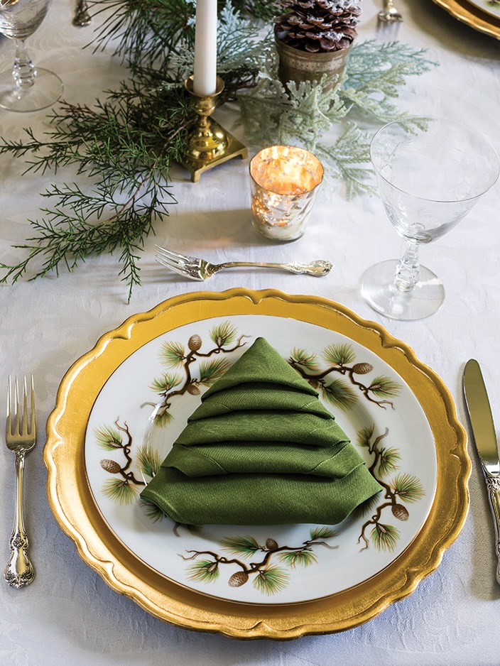 A place setting with a napkin folded into a Christmas tree shape.