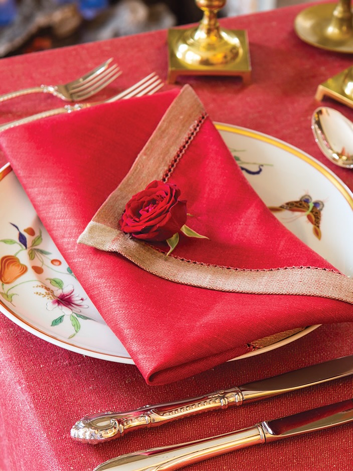 A napkin folded into the shape of an envelope, topped with a rose.