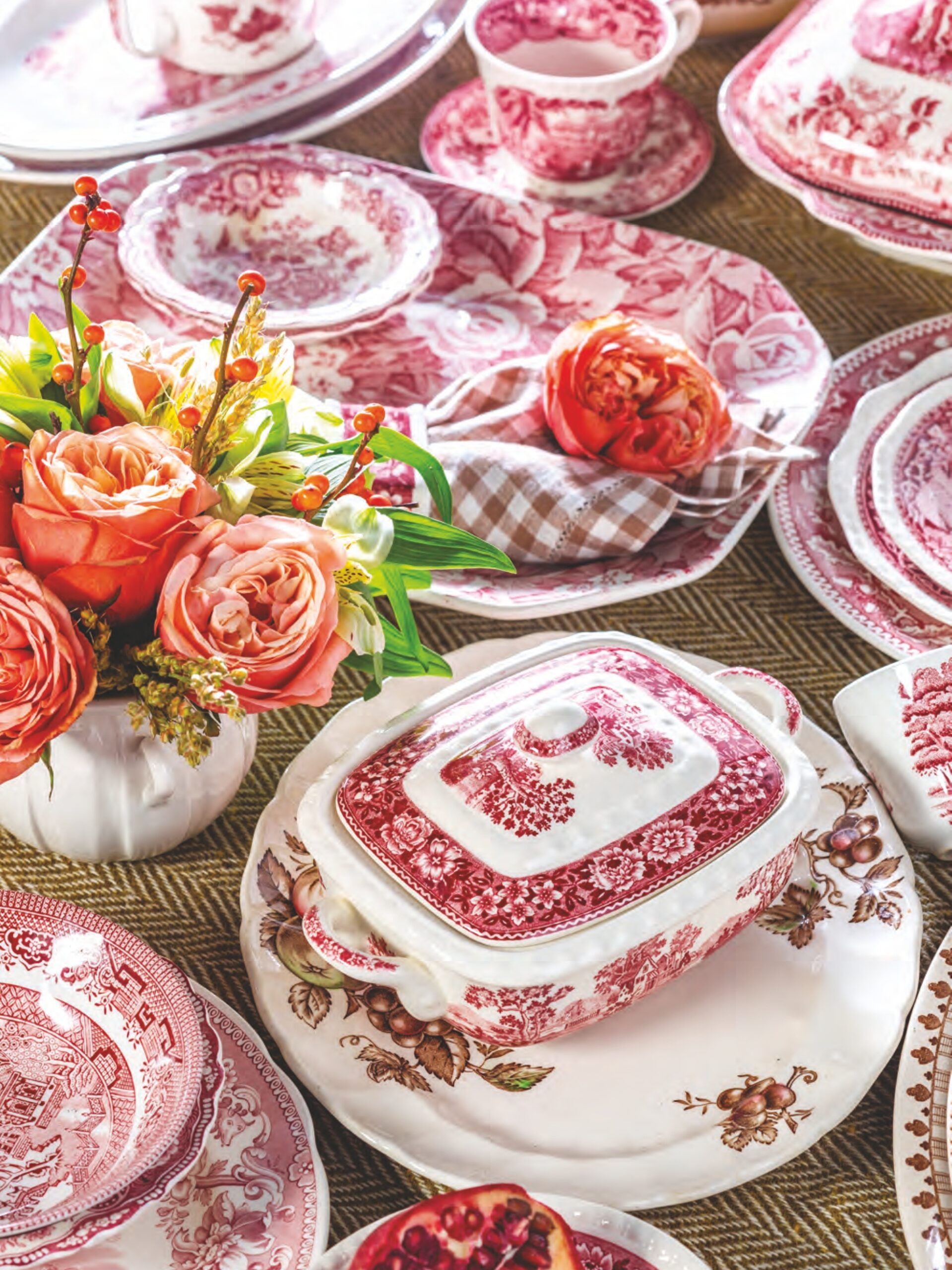 Red and brown transferware plates, butter pats, casserole dishes, and tea cups with flowers.