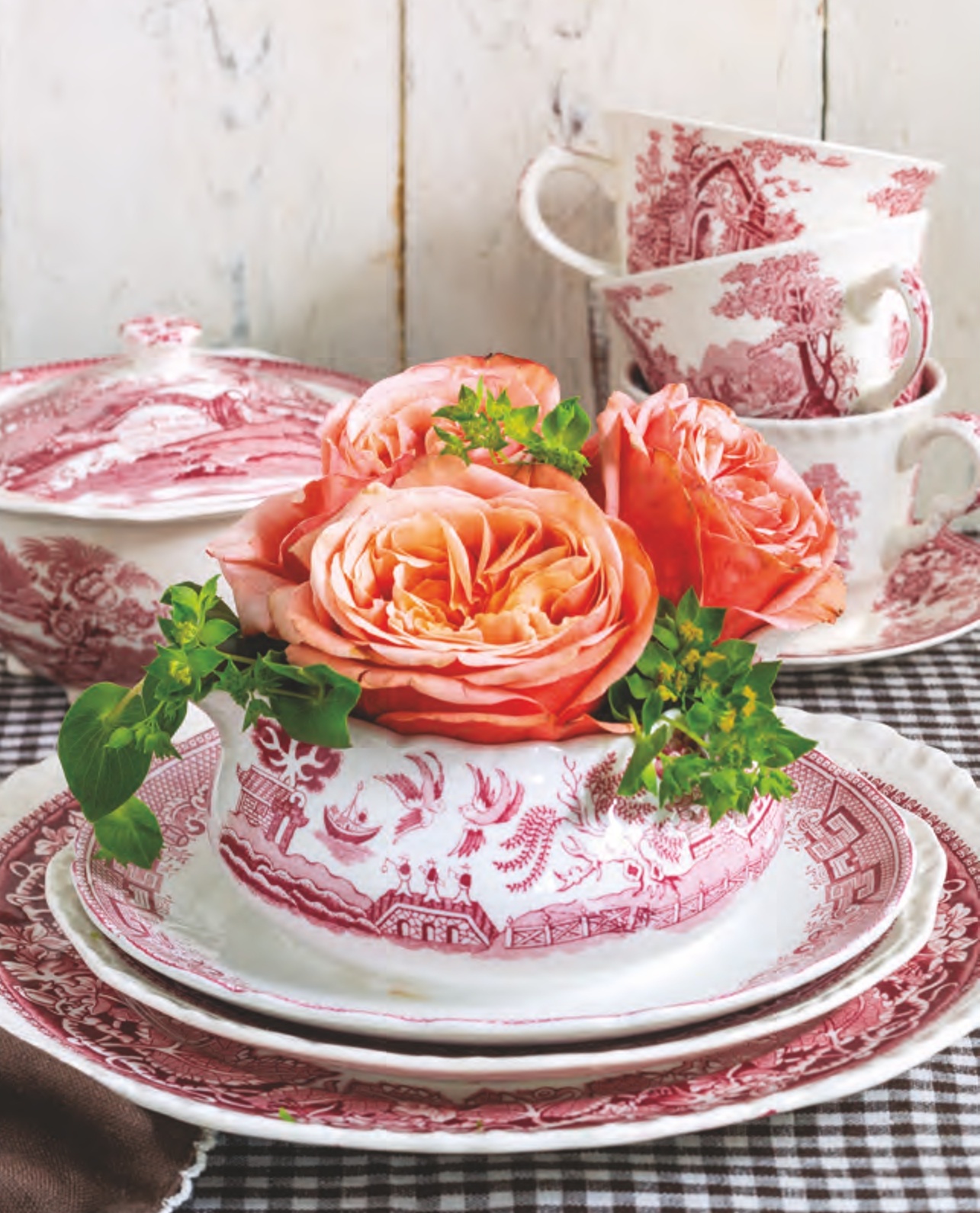 Red transferware gravy boat filled with flowers.