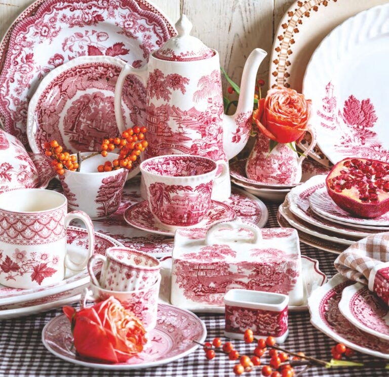 Red and brown transferware plates, butter pats, casserole dishes, pitchers, and tea cups with flowers.