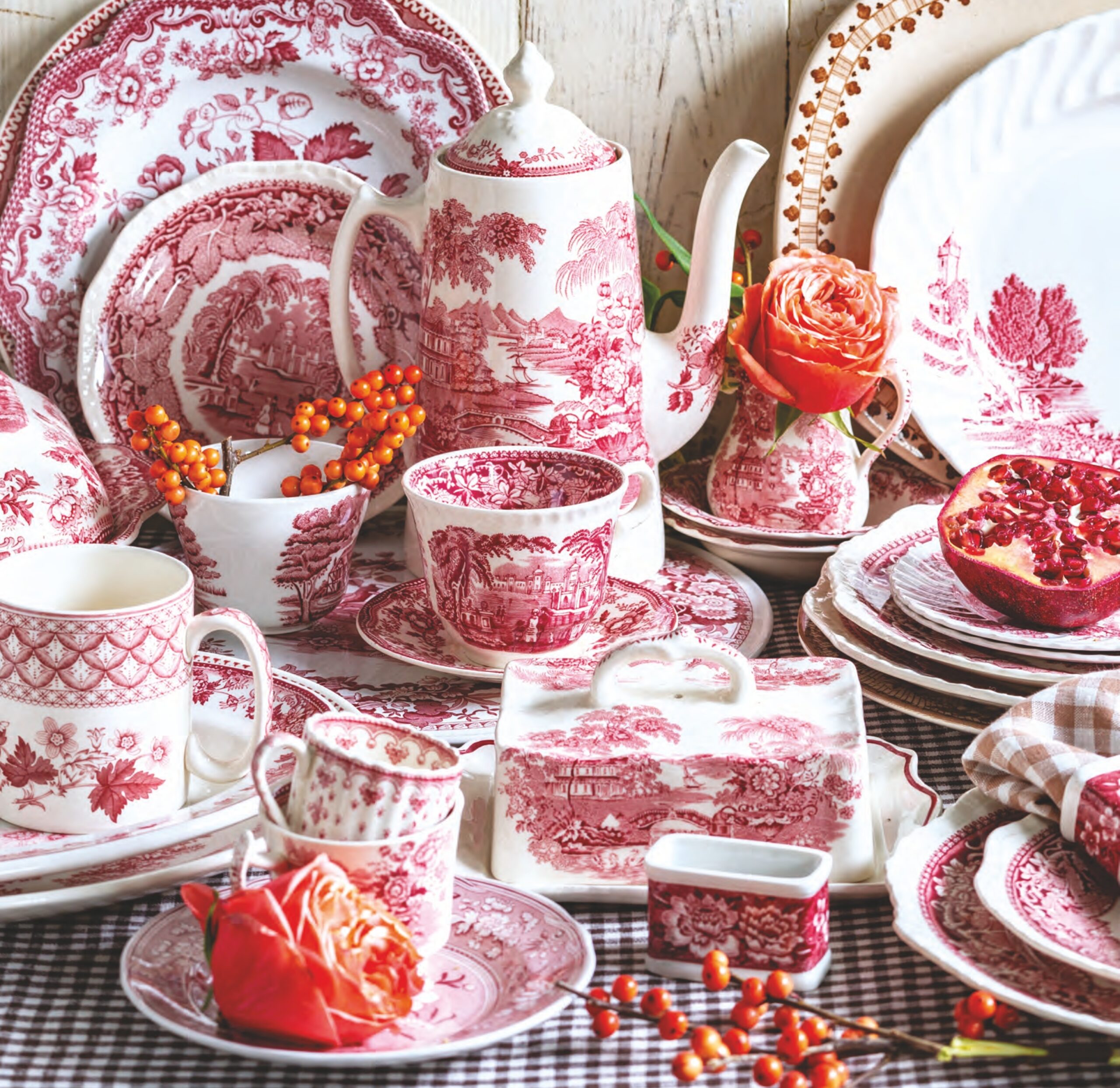 Red and brown transferware plates, butter pats, casserole dishes, pitchers, and tea cups with flowers.