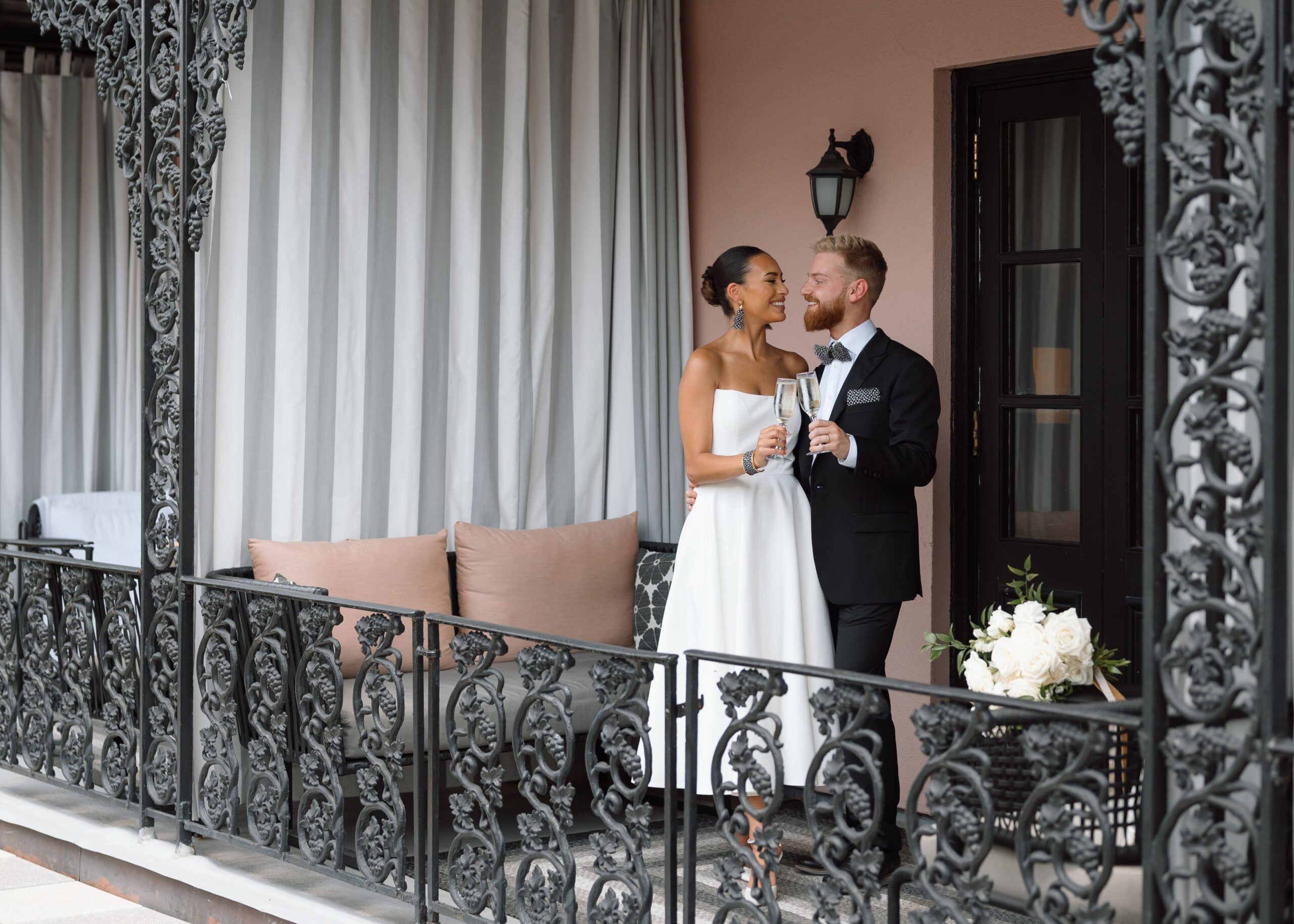 A bride and groom toast each other on the balcony of the Mills House hotel.