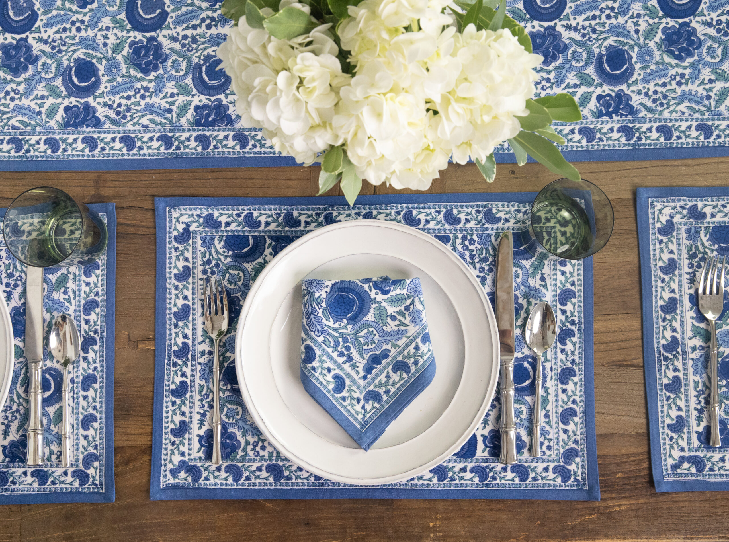 A blue and white place setting with block print napkin, placemat, and table runner.