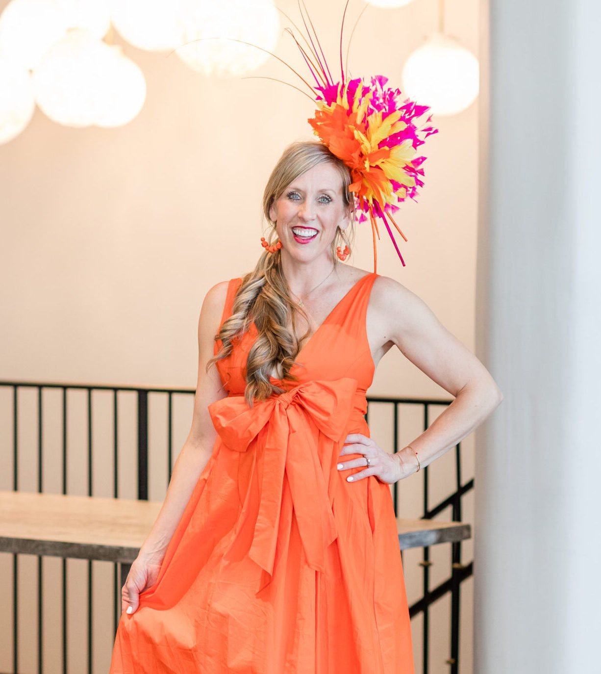Mary Julia Kaiser of Derbyologie wearing an orange dress and one of her matching fascinators for the Kentucky Derby.