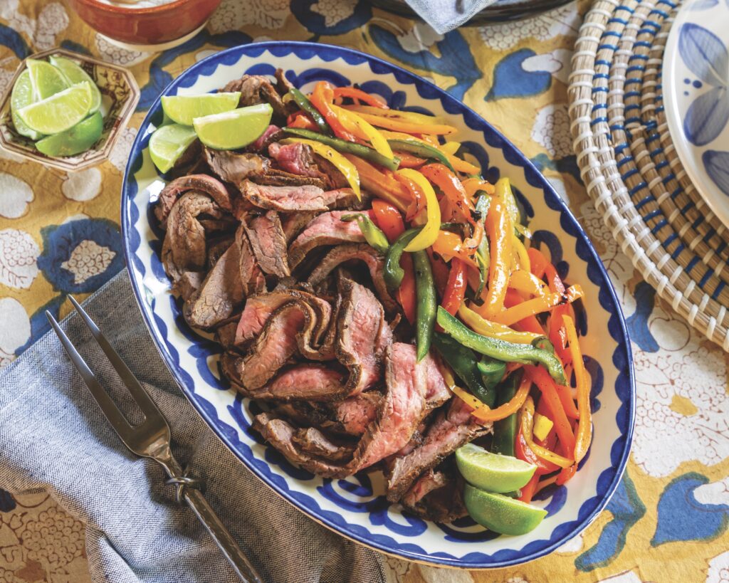 A platter of steak fajitas with colorful bell peppers