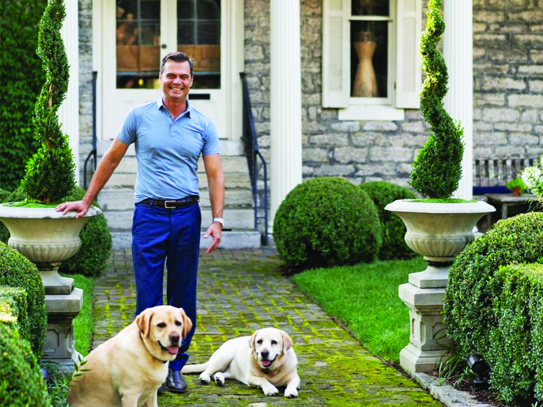Man standing in front of house with 2 labs
